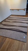 Full view of rectangular rug displayed on hardwood floor under a simple wall shelf.