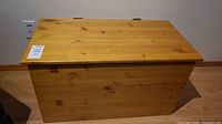 Full closed view of pine toybox showing wood grain and hinged top.
