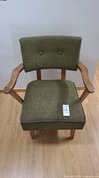 Front view of rocking armchair showing green tufted backrest and wooden arms