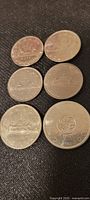 Top view of six Canadian silver dollars arranged showing reverse side with loon and commemorative designs