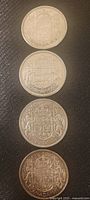 Obverse sides of four Canadian half dollar silver coins featuring the Canadian coat of arms from 1951, 1952, 1957, and 1958.
