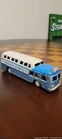 Side view of the Greyhound Scenicruiser tin friction bus toy showing blue and white paint, Greyhound branding, and visible wear.