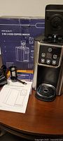 Photo of the iced coffee maker with original box, user manual, and accessories on a table.