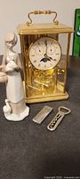 Full view of lot showing Birks brass carriage clock, Japanese figurine, Export A lighter, and German bottle opener