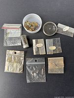 Overview of nine containers holding assorted watch hands and parts