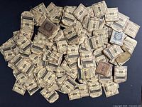 A large assortment of approximately 120 pieces of vintage pocket watch crystals in original packaging spread out on a flat surface.