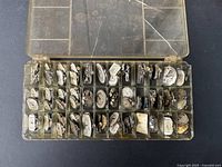 Top view of plastic organizer box containing multiple compartments with vintage women's watch movements and dials mostly in silver tone, various shapes and dial faces visible.