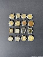 Overhead view of 16 vintage watch cases arranged in a 4×4 grid