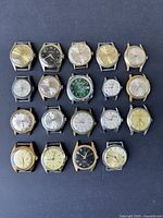 Straight overhead photo showing all 19 vintage men's wristwatches arranged in rows without bands, various dial colors and conditions