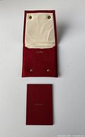 Open red suede Cartier bracelet pouch showing beige interior and snap buttons with Cartier logo inside.