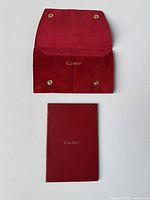 Open red suede Cartier jewelry pouch showing snap button closure and Cartier logo inside.