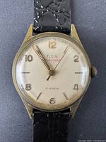 Close-up front view of vintage Elgin Sportsman watch face showing 17 jewels marking and gold-tone case.