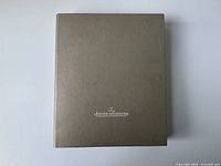 Overview photo of textured brown hardcover catalog book with white Jaeger-LeCoultre logo.