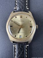 Front view of gold-tone vintage Continental Swiss men’s watch with black stitched leather strap, cushion-shaped case, and visible wear on case and dial.