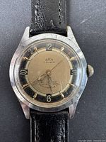 Front view of vintage men's wristwatch showing dial, brand name EKA and condition of leather strap, watch case and crystal.