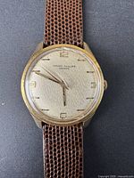 Close-up photo of vintage Girard-Perregaux watch face showing gold-tone dial, numerals 3, 6, 9, 12 and textured dial pattern.