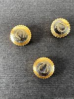 Top-side view showing three gold-plated watch crowns with the Omega logo embossed on black tops.