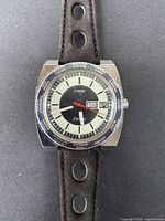 Front close-up of the Timex watch showing dial and bezel with city names, day-date display, and red second hand.