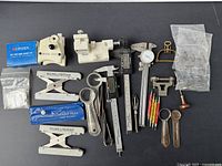 Overview of vintage watch repair tools including measuring devices, screwdrivers, files, clamps, and specialized Baume & Mercier band adjusters.