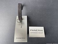 Top view of Panerai metal display stand and authorized dealer plaque on grey surface
