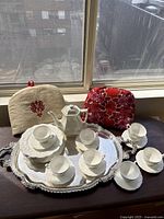 Overview of lot on window sill including teacups, saucers, plates, teapot, tray and tea cosies