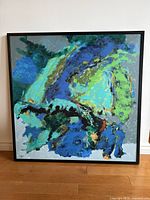 Front view of the framed oil painting showing full abstract composition on hardwood floor against white wall