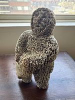 Full front view of carving on windowsill showing hunter figure and seal across shoulders