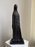 Front view of the black standing figure sculpture on a pedestal