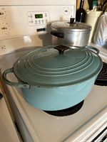 Front side view with lid on, showing teal blue exterior, side handles and overall condition