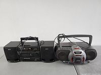 Two Sony boombox units side by side, black CFS-1055 on left with two external speakers and silver CFD-G55 on right with dual cassette decks and carry handle.