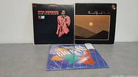 Three LP albums standing and lying on a flat surface: Otis Redding Live In Europe, Ahmad Jamal Sun Ra, and a colorful geometric cover album.