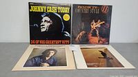 Four country music vinyl record albums placed on a flat surface, front covers visible including Johnny Cash and other artists.