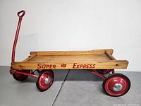 Side view of the wooden wagon with red frame, showing the 'Super CTC Express' lettering on the side panel and metal wheels with hubcaps.