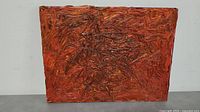 Front view of the textured abstract painting showing reddish and orange tones with heavy impasto technique.