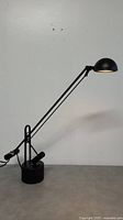 Full view of the black vintage cantilever table lamp showing adjustable arm and cylindrical weighted base.