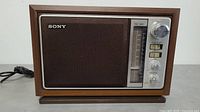 Front view of the vintage Sony radio showing speaker grill, tuning dial, control knobs and switches.