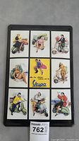 Full view of the rectangular metal sign showing the nine illustration panels featuring women and Vespa scooters.