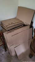 Stacked flat-packed cardboard boxes in three sizes and banker boxes nearby