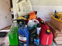 Wide view of various car wash and detailing fluids including green liquid, Simoniz wash and wax, Esso brake fluid, transmission fluid, and red gas containers.