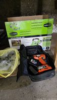 Bag containing Black & Decker drill and charger alongside GreenWorks blower box and yellow bag with padlocks.