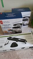 Photo showing two boxed sets of stainless steel mixing bowls branded President's Choice and a Cuisinart mandoline box.