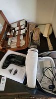 Vintage men's grooming set with brushes, comb, mirror in leather travel case alongside Omron blood pressure monitor and HoMedics mini massager in packaging foam