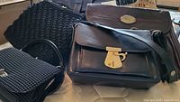 Five vintage purses arranged showing varied styles, mostly black woven and some brown leather purses.