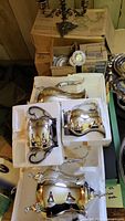 Photo showing two small silver plated candelabras and additional boxed silver items