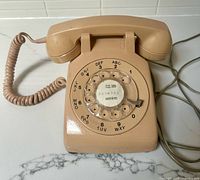 Top view of pink rotary desk telephone showing full dial and handset