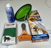 Group shot showing all five items: deshedding tool, PediPaws box, PawZ boots pack, saline wound wash spray, collapsible bowl