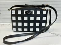 Front view of purse showing grid pattern and Kate Spade New York plaque