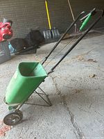 Side view of push spreader showing hopper, handle, wheels