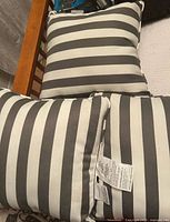 Three striped square outdoor pillows stacked showing pattern and size