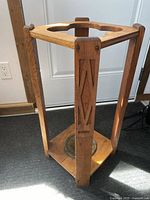 Side view of solid wood umbrella stand showing carved wood panels and brass base